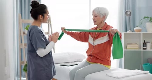 Elderly woman doing exercise with a resistance band for physical therapy with nurse in clinic
