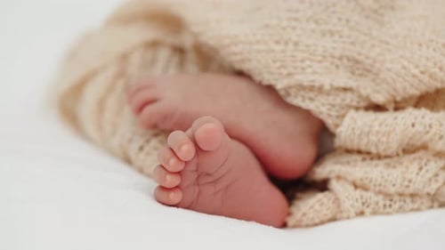 close up feet of newborn baby on a bed