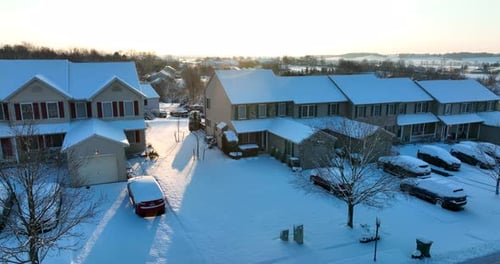 Residential townhouse homes covered in fresh winter snow in USA. Morning sunlight on houses.