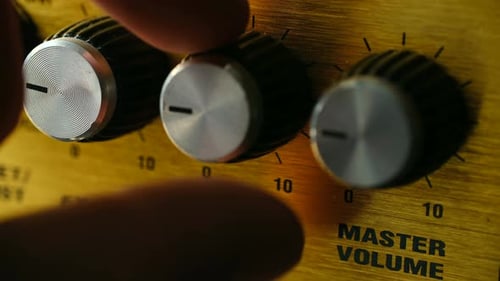 Hand Adjusting Reverb and Volume Knobs on Amplifier