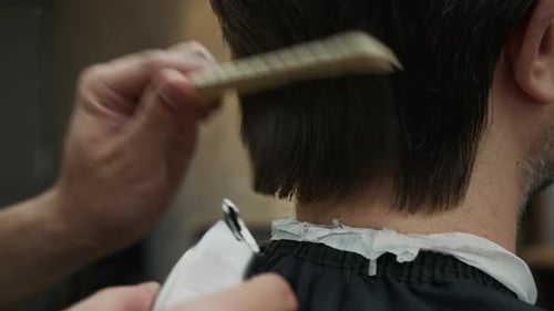 Hairdresser Shaving Mans Hair with Clipper at Barbershop