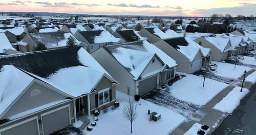 New modern homes in USA covered in winter snow at Christmas. Colorful sunset aerial establishing sho