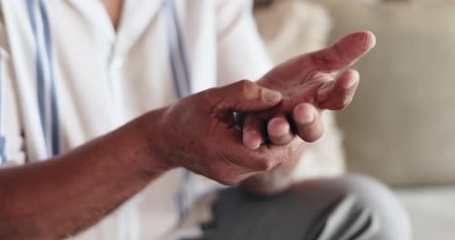 Manos, dolor y artritis con masaje en casa en el sofá con muñeca, lesión