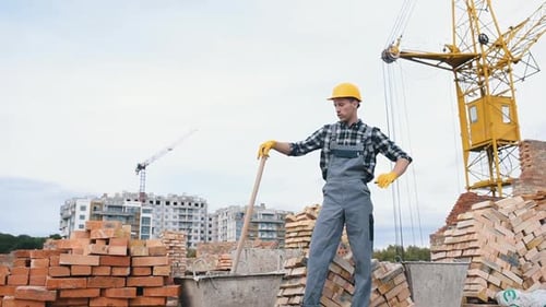 Uses shovel. Construction worker in uniform and safety equipment have job on building