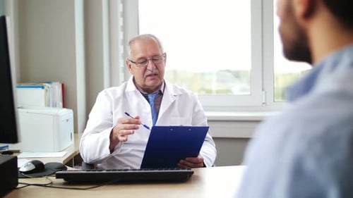 Médico sénior discute un problema de salud con un paciente joven en el hospital