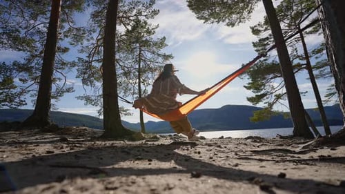 Traveling Woman in a Hat is Resting in an Orange Hammock