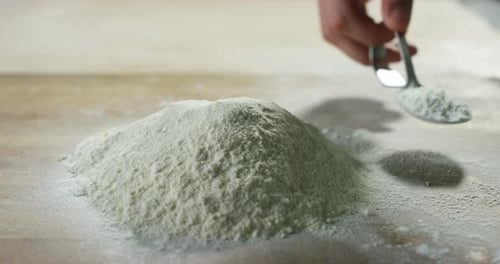 An experienced chef in a professional kitchen prepares the dough with flour to make the bio Italia