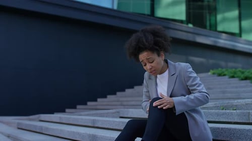 Mulher sentada nos degraus com dor no joelho