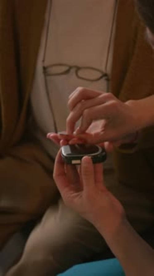 Close-up of Elderly Woman Receiving Blood Sugar Monitoring from Nurse at Home