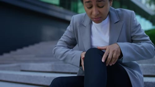 Empresária com dor no joelho sentada na escada