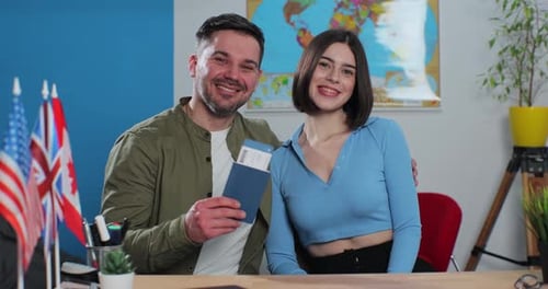 Portrait of a Happy Young Couple in a Travel Agency They are Getting Plane Tickets for a Summer Trip
