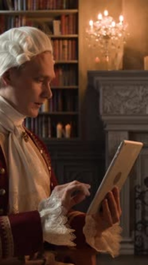 Vertical of Actor in Historical Costume Using Digital Tablet on Movie Set