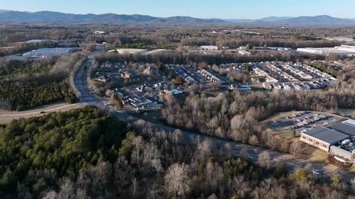 Suburb housing area of american with between leafless forest trees and intersection road. Aerial app