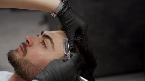 Professional Female Barber Carefully Shaves Male Client with Straight Razor at Upscale Barbershop