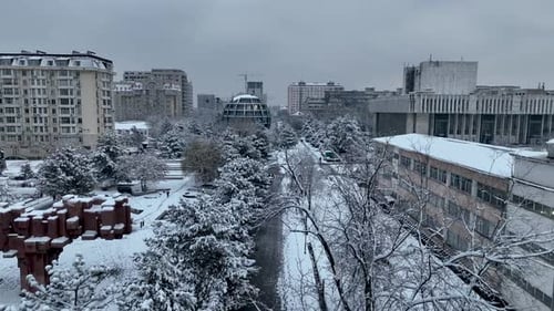 Monument, snow covered park and modern city skyline in Bishkek