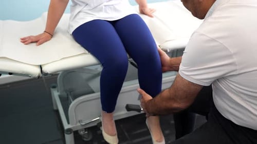 Physiotherapist examining female patient testing her knee stability