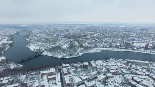 View of the big city with river floating through it on snowy winter day.
