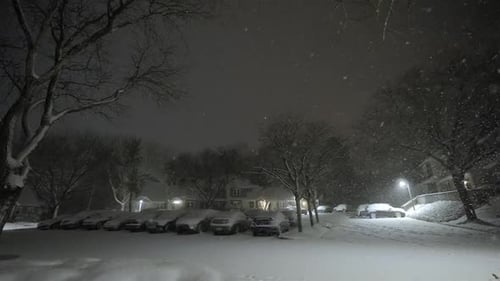 Snowflakes falling down on a winter evening, parking cars in an urban area at night, cold snowfall