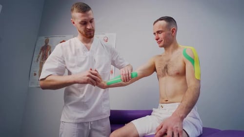 Kinesiology The Physiotherapist Applies Kinesio Tape to the Male Body