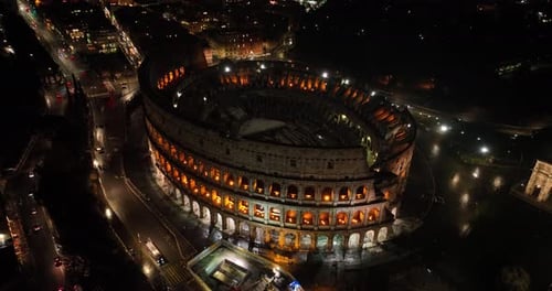 Aerial fly drone view of Colosseum or Coliseum at night, Rome, Italy, Europe. Ancient Roman ruin is