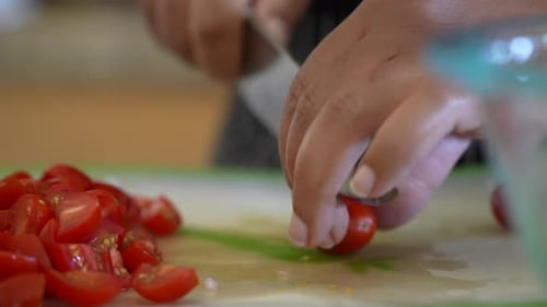 Focus pull to reveal the hands of a black woman cutting cherry tomatoes for a chopped salad - ANTIPA