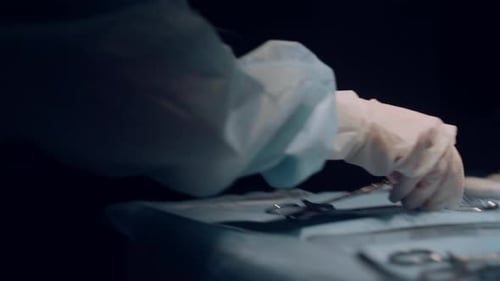 Assistente entregando ferramentas cirúrgicas a um profissional em closeup do Dark Operating Theater. Profissional desconhecido