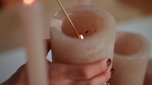 Closeup Female Hand Lightning Christmas Candle with Match in Slow Motion
