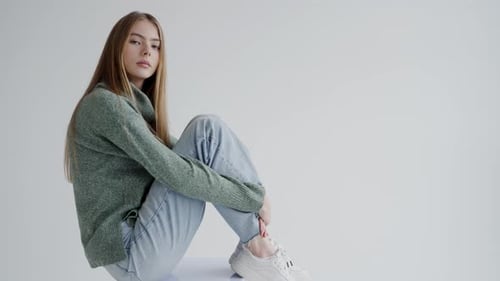 Young Woman in Casual Green Sweater and Denim Jeans Posing