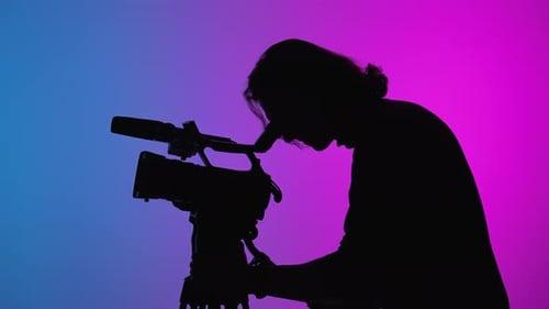 Silhouette of a Videographer Filming with Professional Camera