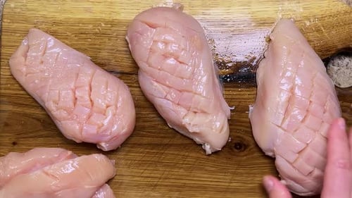 Raw chicken breasts, with cuts to allow better penetration of the marinade