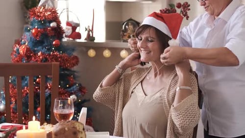 Mujer poniendo un collar alrededor del cuello de su pareja para Navidad