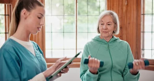 Senior woman with weights for exercise with physiotherapist at physical therapy clinic
