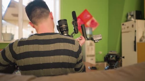 Back View of Studio Guy Adjusting Camera on Tripod with Microphone for Filming Project