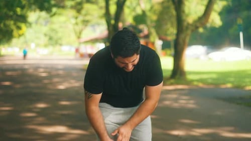 Young man getting knee injury while running at the park