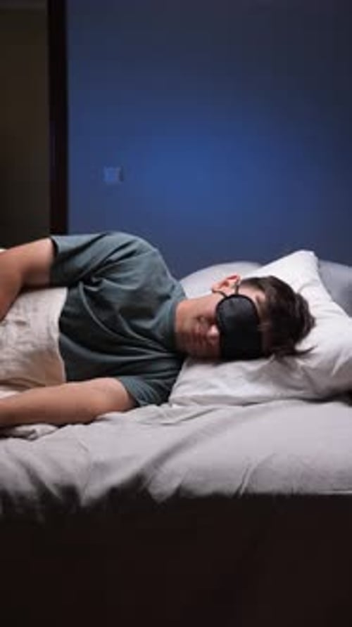 Vertical Video Man Sleeping Peacefully with Sleep Mask in Bed Rest Relaxation