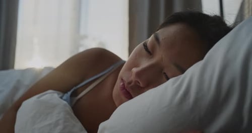 Beautiful Woman Sleeps on Soft Pillow in Cozy White Bed
