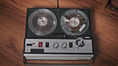 Vintage Tape Recorder with Rotating Reels on Wooden Surface