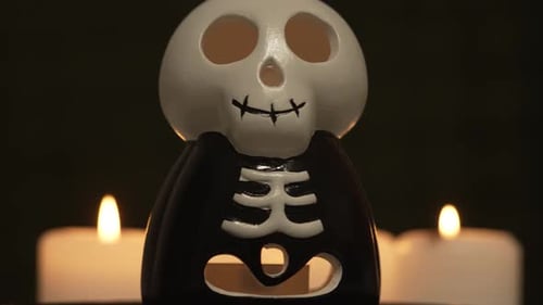 Skeleton Skull Head with Scary Grin Glows and Spinning on Halloween Night with Burning Candles