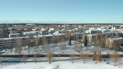 Aerial, tracking, drone shot, of snowy streets, buildings, leafless trees, in the cityscape of Joens