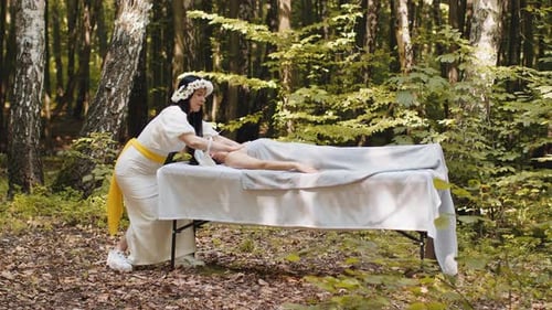 Médica terapeuta fazendo massagem facial relaxante no spa com as mãos ao ar livre na floresta