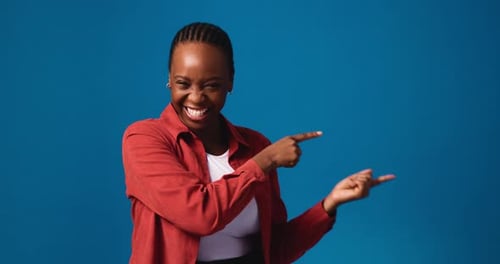 Happy, black woman and pointing with advertising in studio for marketing on a blue background