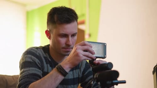 Person Adjusting LED Video Light While Setting Up Camera Equipment