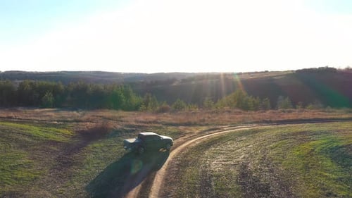Aerial Shot of Black Car Driving Along Road Near Field Off Road Vehicle Riding Through Rural Path