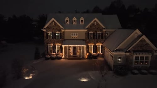 Festive Christmas lights and snow-covered home at night. Illuminated stone house on snowy night. Aer