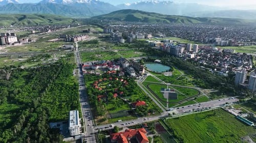 Aerial view of modern city Bishkek with green parks and snow covered mountains