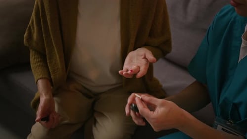 Nurse Using Glucometer, Checking Blood Glucose Level of Elderly Woman at Home