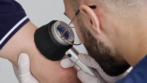Male Dermatologist Using Dermatoscope while Examining Skin Condition