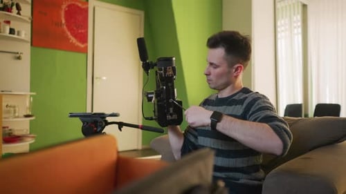 Studio Guy Adjusting Camera on Tripod in Home Studio Preparing for Video Shoot