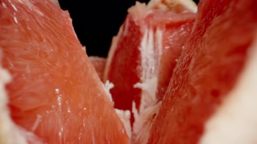 Whole and sliced grapefruits on the table. Inside with red flesh. Dolly slider, close up.