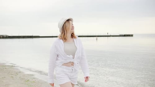Portrait of a Smiling Blonde Woman Enjoying Her Vacation on the Beach Wearing a Stylish White Hat